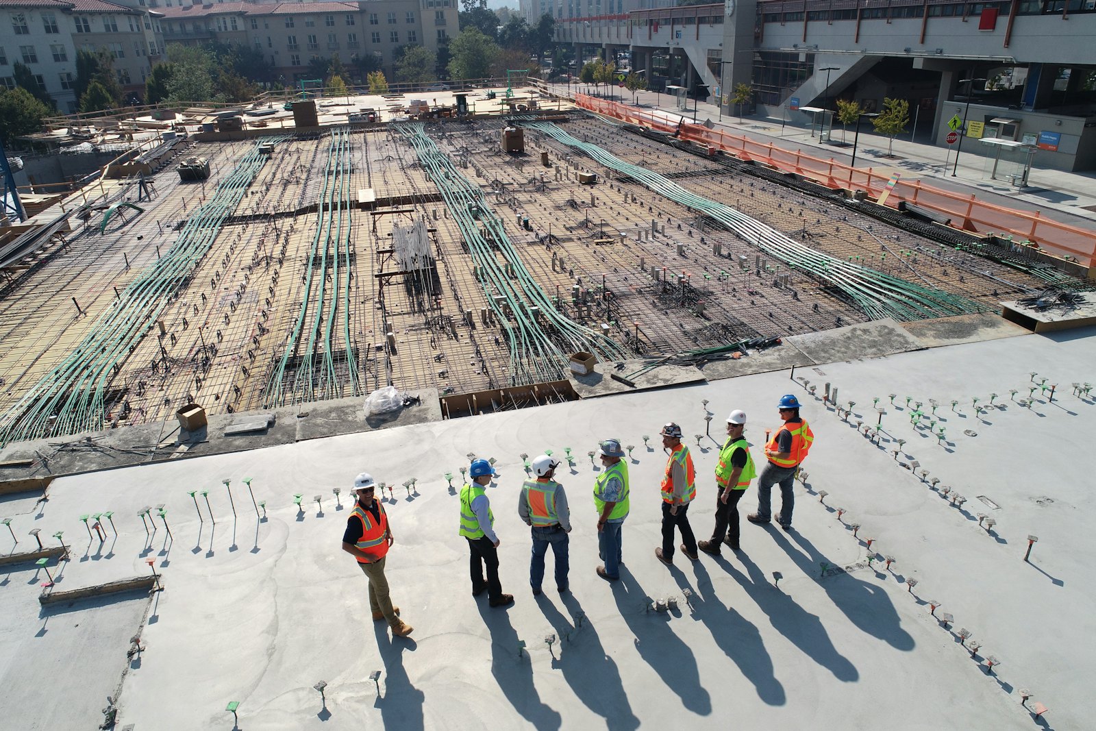 Construction team in safety vests inspecting a large reinforced-concrete slab on site