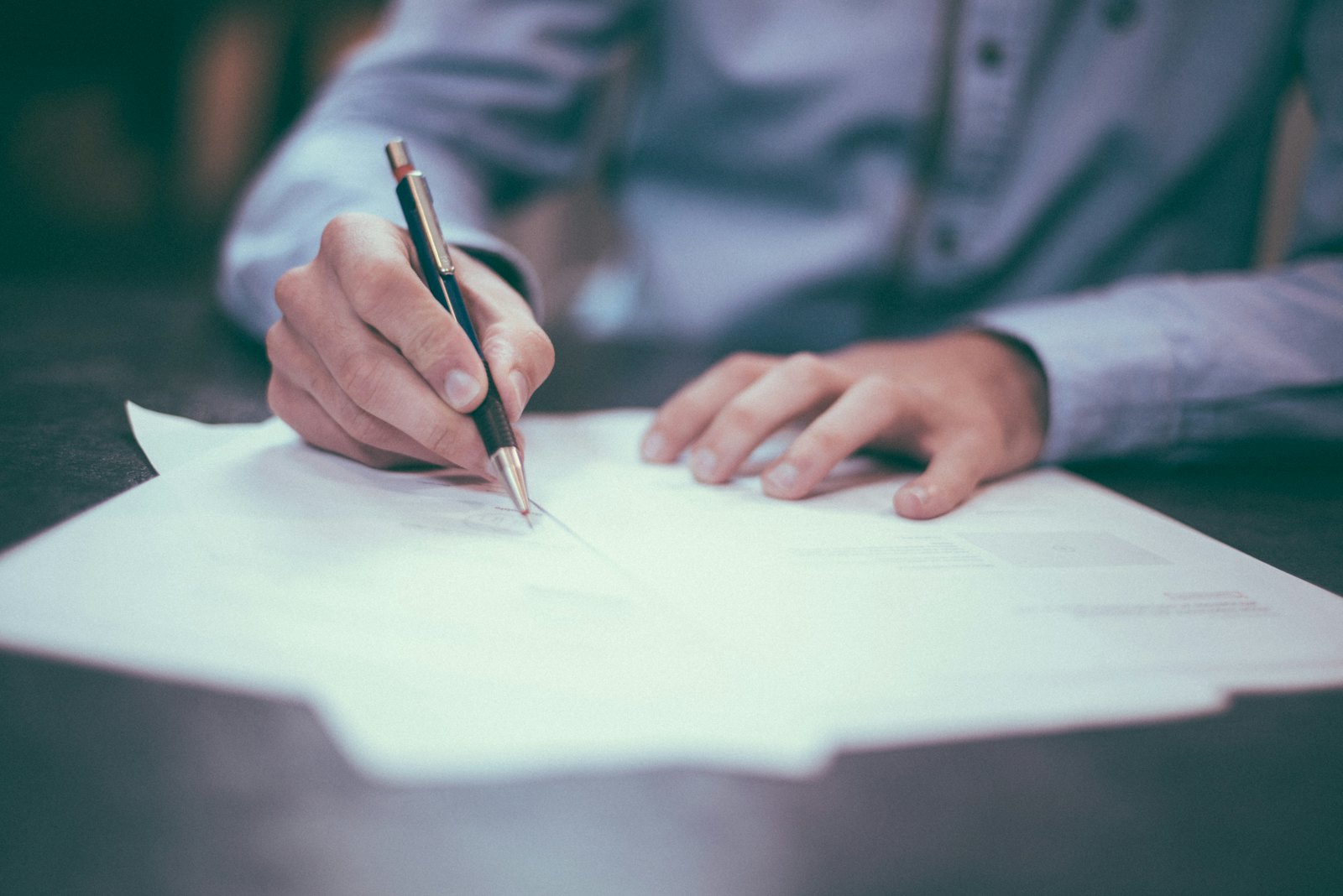 Person unterzeichnet ein Vertragsdokument mit einem Stift